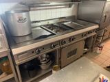 une grande cuisine en inox avec une cuisinière et une casserole posée sur le plan de travail