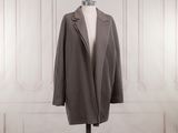 the coat is on a mannequin stand in front of a white wall