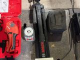 une boîte à outils rouge contenant un marteau, une perceuse, un marteau et d'autres outils, posée par terre