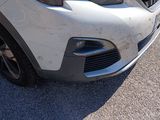 the front end of a white car with a denting dent on it