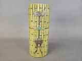 a yellow vase with a key on it sitting on a table
