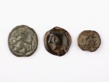 trois pièces de monnaie romaines anciennes, dont l'une représente un visage et l'autre une tête