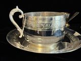 une tasse et une soucoupe en argent posées sur une soucoupe
