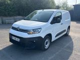 la camionnette blanche est garée sur un parking avec des arbres en arrière-plan