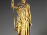 an image of a gold statue of a woman holding a staff