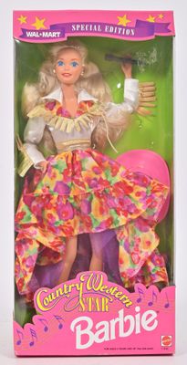 La poupée Barbie se trouve dans la boîte, vêtue d'une robe rose.
