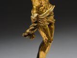 a gold statue of a man holding a cross on a black base