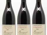 trois bouteilles de vin rouge sont alignées sur une surface blanche