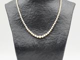 un collier de perles blanches sur un mannequin avec un fermoir en or