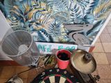 a dart board and a cup on the floor next to a wall