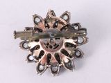 a silver brooch with a flower design on it