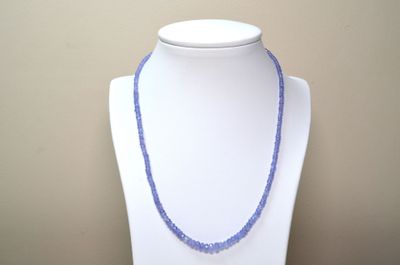 collier de perles violettes sur un mannequin blanc orné d'une perle bleue