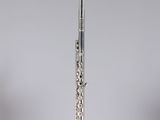 a silver flute on a clear stand against a gray background