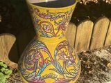 a yellow vase sitting on the side of a wooden fence