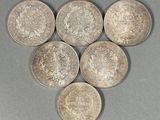 six pièces d'argent de tailles et de formes différentes posées sur une surface grise