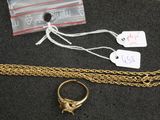 a gold ring and a gold chain on a table