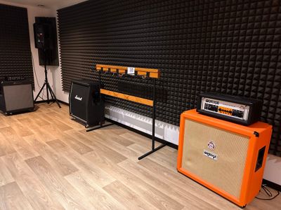 a room with a guitar, amplifier, and speakers in it