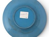 a blue plate with a sticker on it on a white surface