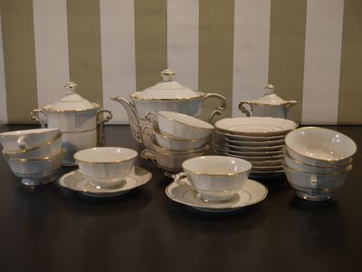 de nombreuses tasses et soucoupes posées sur une table recouverte d'un papier peint rayé
