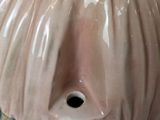 a pink vase with a face on it sitting on a table