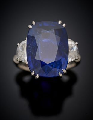 un gros plan d'une bague en saphir et diamants posée sur une surface noire