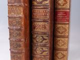 several old books are stacked on top of each other on a white surface