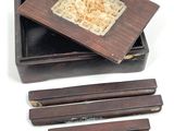 a small box with four wooden chopsticks and a wooden box with four chopsticks in it
