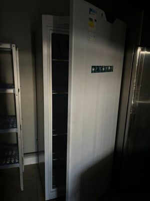 un réfrigérateur dans un coin d'une pièce, dont la porte est ouverte