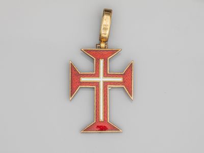 un pendentif en forme de croix rouge et dorée, orné d'une croix blanche