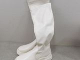 pair of white boots on a gray surface with a white wall in the background