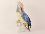 a figurine of a parrot sitting on a tree branch