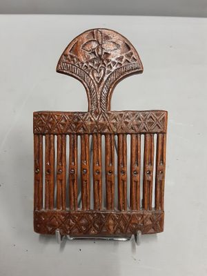 une image représentant un peigne en bois orné d'un motif décoratif sur le dessus