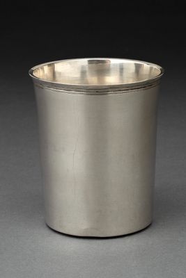 une coupe en argent posée sur une surface grise avec un fond noir