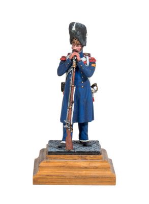 the figurine of a soldier with a rifle stands on a wooden base