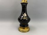 une photo d'un vase noir et doré posé sur une table blanche