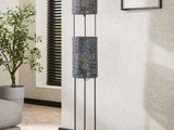 a black floor lamp with three shades on it in a living room