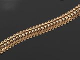 gros plan d'un bracelet en or sur une surface noire