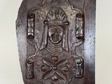 carved wooden plaque of a woman holding a sword and a shield