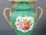 un vase vert orné d'une anse dorée et d'un motif floral