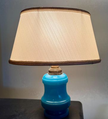 une lampe de table bleue surmontée d'un abat-jour beige