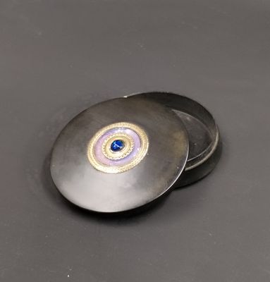 un petit objet métallique sur lequel est représenté un œil bleu