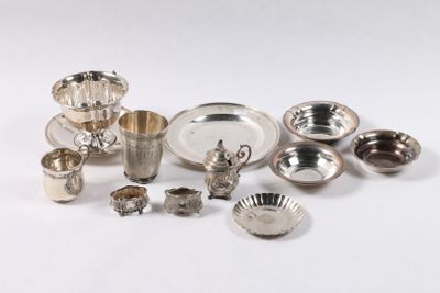 Plusieurs plats et tasses en argent sont disposés sur une surface blanche