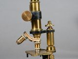 an old microscope with a metal base and a wooden base