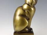 an image of a bronze cat statue sitting on top of a wooden block