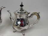 two silver teapots sitting next to each other on a table