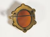 a gold brooch with a red stone in it