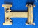 an antique brass letter h on a blue background