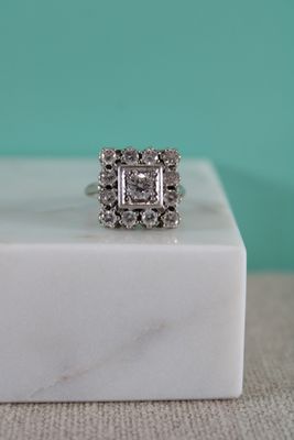 un gros plan d'une bague en diamant posée sur un bloc de marbre