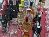 many bottles and glasses on a table with a red table cloth