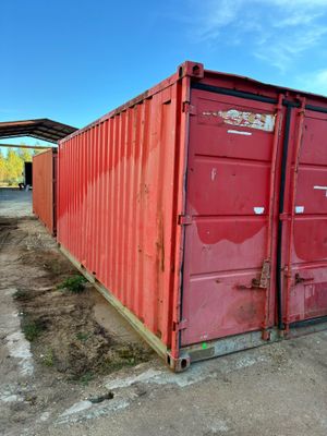 a red shipping container sitting in the middle of a dirt field